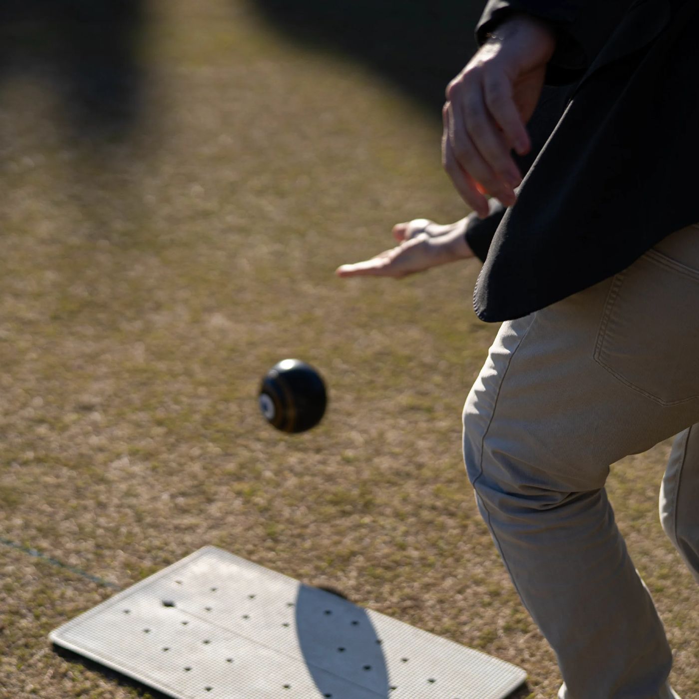 A barefoot bowler rolling a bowl on the green