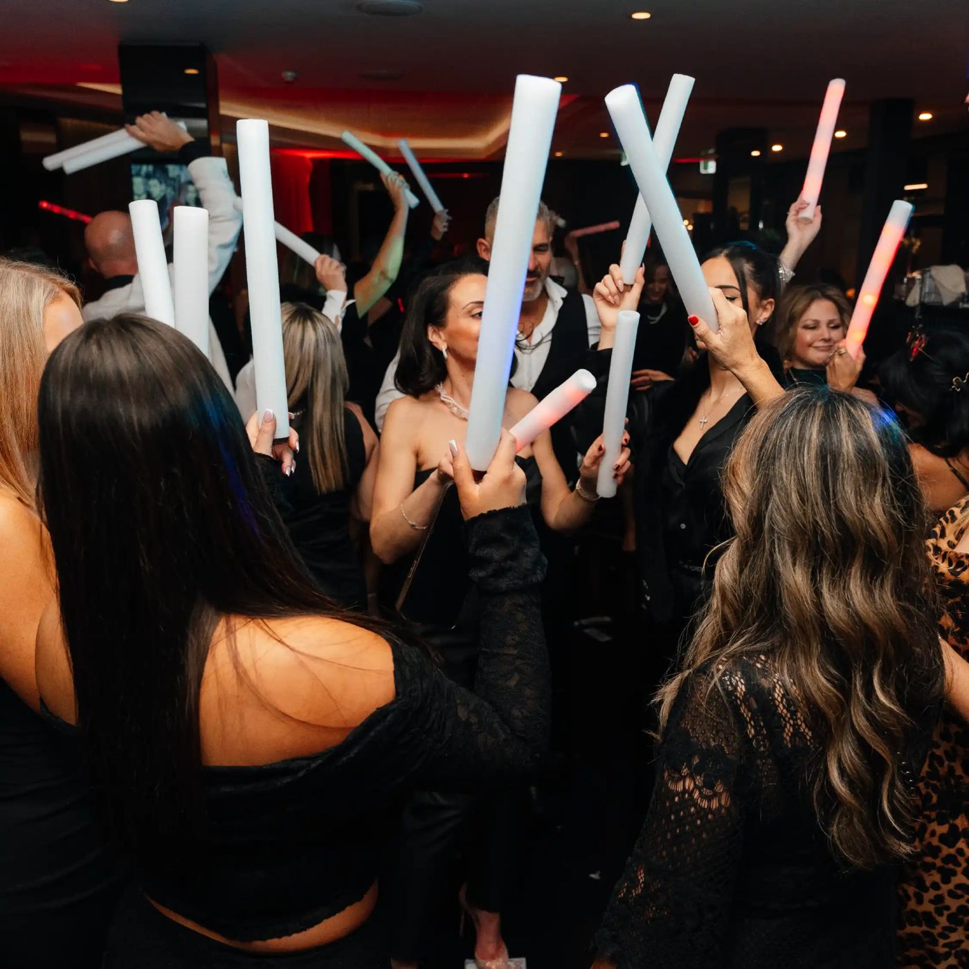 A crowd dancing with light sticks in the club auditorium