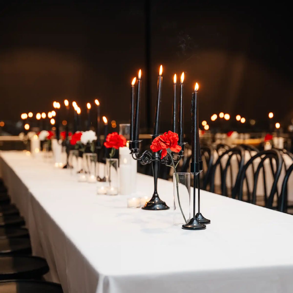 A long table with black candelabras and red flowers