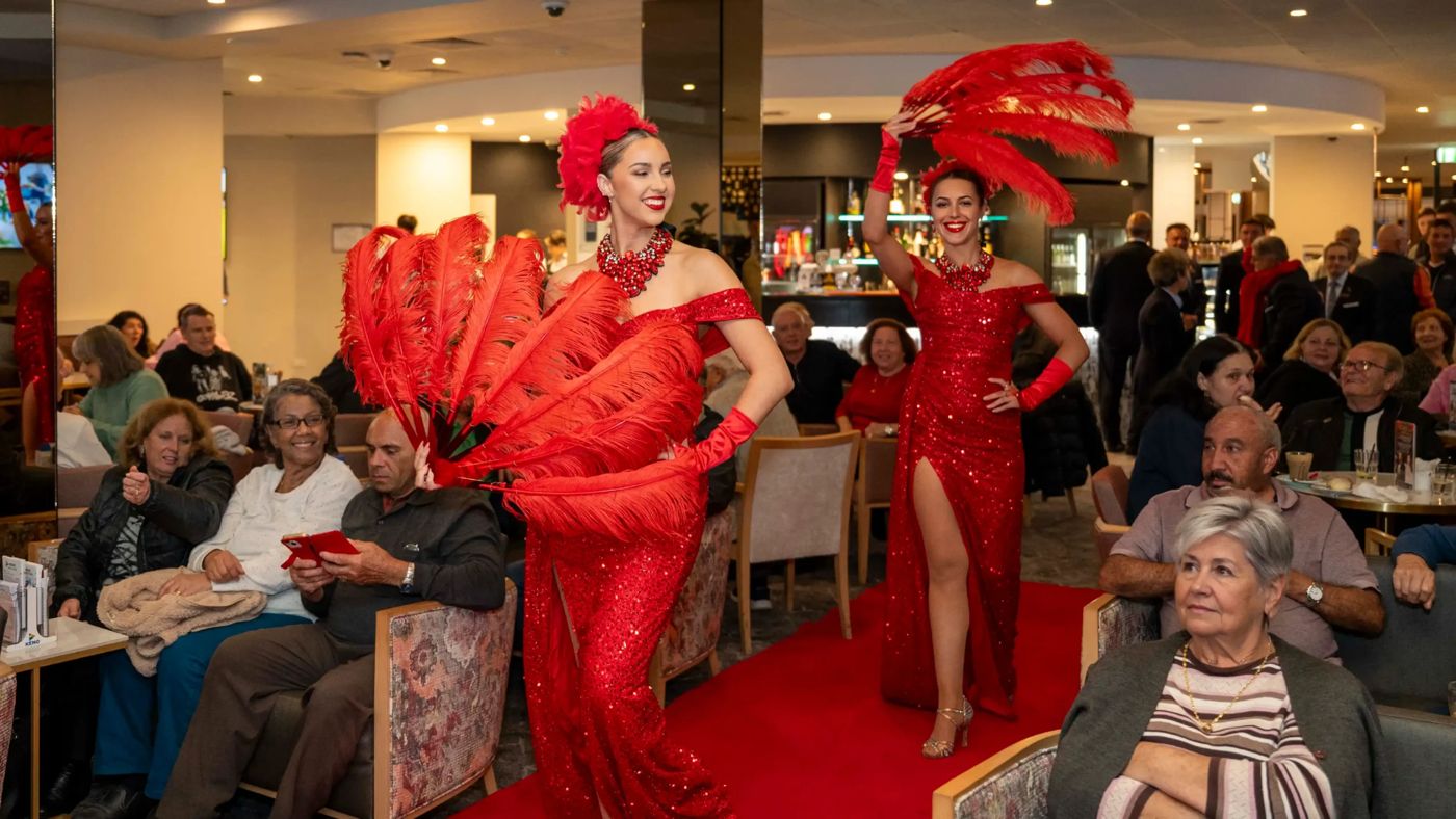 Performers in red feathered costumes entertaining a full dining room at the club